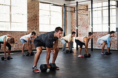Buy stock photo Shot of a group of people preparing to lift dumbbells in a fitness class