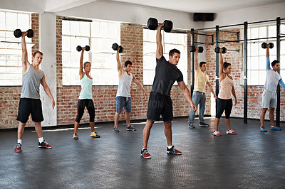 Buy stock photo Shot of a group of people lifting dumbbells in a fitness class
