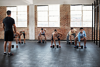 Buy stock photo Shot of a group of people preparing to lift dumbbells in a fitness class