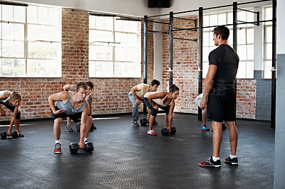 Buy stock photo Shot of a group of people preparing to lift dumbbells in a fitness class