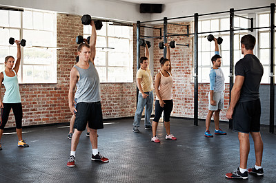 Buy stock photo Shot of a group of people lifting dumbbells in a fitness class