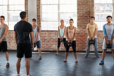 Buy stock photo Shot of a group of people lifting kettlebells in a fitness class