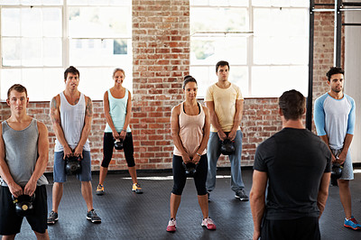 Buy stock photo Shot of a group of people lifting kettlebells in a fitness class