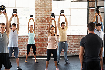 Buy stock photo Shot of a group of people lifting kettlebells in a fitness class