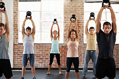 Buy stock photo Shot of a group of people lifting kettlebells in a fitness class