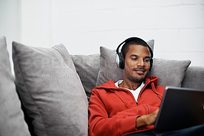 Buy stock photo Shot of a young man listening to music on his digital tablet