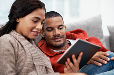 Buy stock photo Shot of a happy young couple using a digital tablet together on the sofa at home