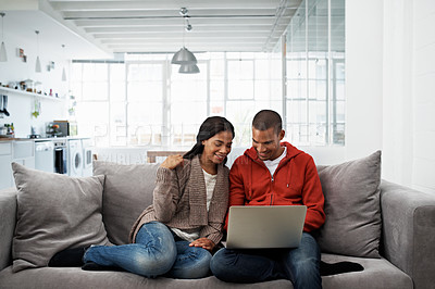 Buy stock photo Shot of a happy young couple using a laptop together on the sofa at home