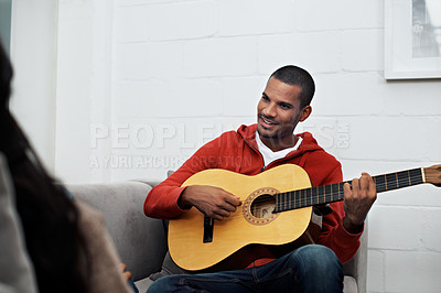 Buy stock photo Shot of a young man playing the guitar at home