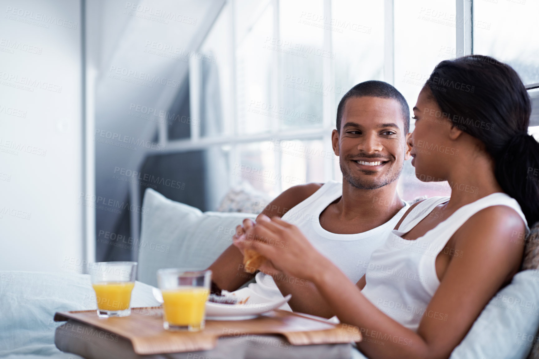 Buy stock photo Relax, breakfast and happy couple with food in bed for morning meal, diet or nutrition together. Man, woman or chilling with smile, orange juice or snack in bedroom for eating or date in house