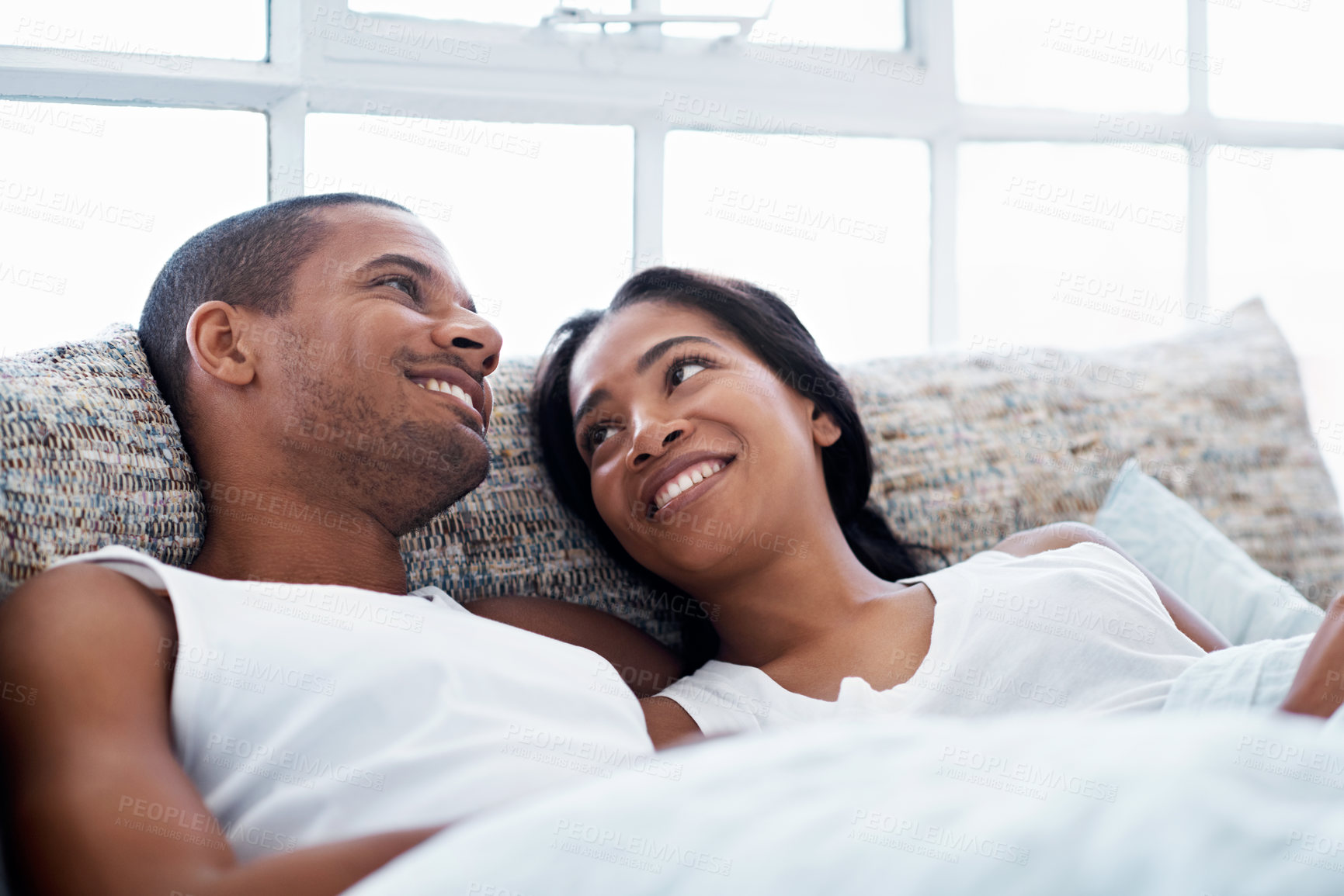 Buy stock photo Happy, relax and couple on bed in home with bonding, love and connection in marriage on holiday. Smile, care and man with woman in bedroom for commitment in relationship on weekend break in house.