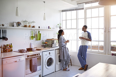 Buy stock photo Full length shot of a young couple having coffee in the kitchen