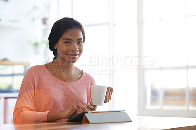 Buy stock photo Cropped portrait of a young woman drinking coffee and using her tablet in the kitchen