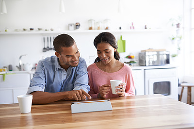Buy stock photo Cropped shot of a young couple drinking coffee and using their tablet in the kitchen