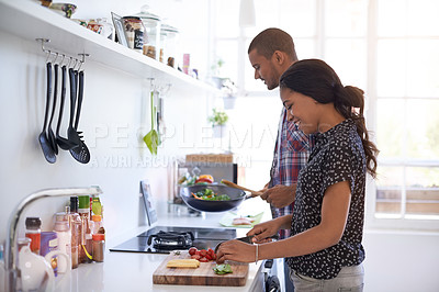 Buy stock photo Cropped shot of a young couple preparing dinner in their kitchen