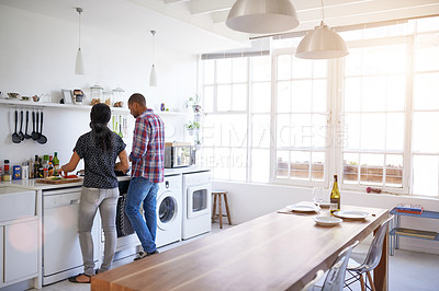 Buy stock photo Rearview shot of a young couple preparing dinner in their kitchen