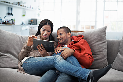 Buy stock photo Cropped shot of a young couple using their tablet while sitting on the sofa at home