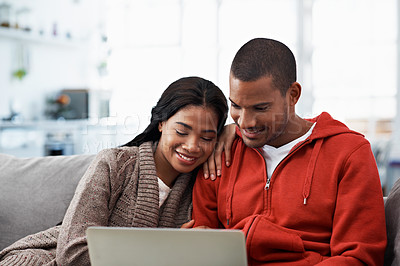 Buy stock photo Cropped shot of a young couple using their laptop while sitting on the sofa at home