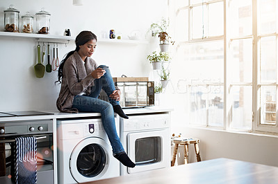 Buy stock photo Full length shot of a young woman using her cellphone in the kitchen