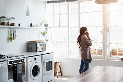 Buy stock photo Cropped shot of a young woman using her cellphone in the kitchen