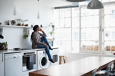Buy stock photo Full length shot of a young woman using her cellphone in the kitchen