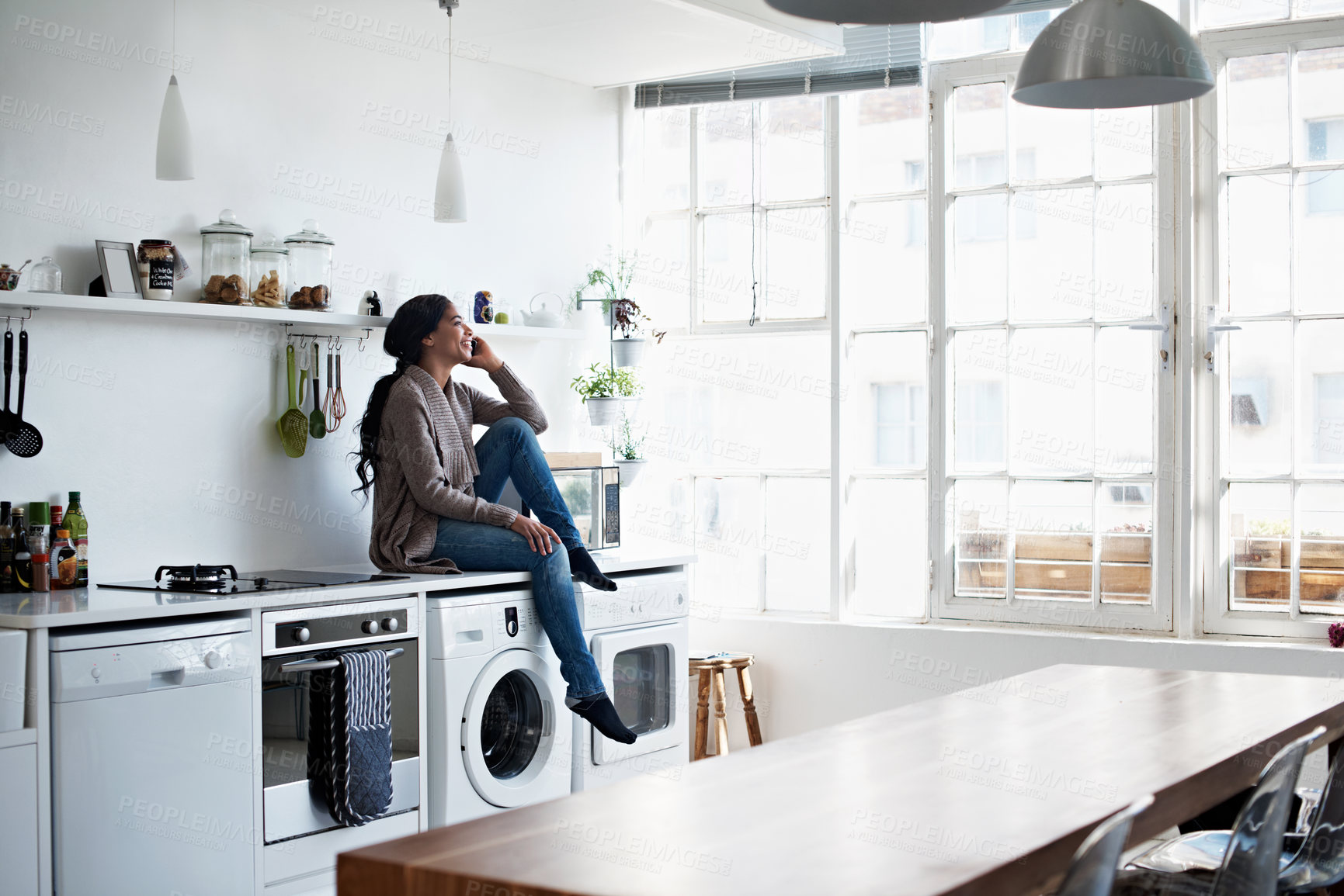 Buy stock photo Full length shot of a young woman using her cellphone in the kitchen