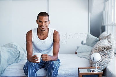 Buy stock photo Portrait of a young man sitting on his bed drinking coffee