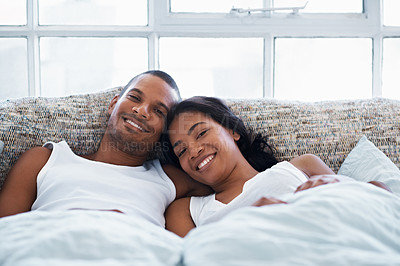 Buy stock photo Portrait of a smiling young couple lying in bed