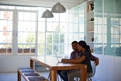 Buy stock photo Shot of a young couple sitting at their dining table using a latpop