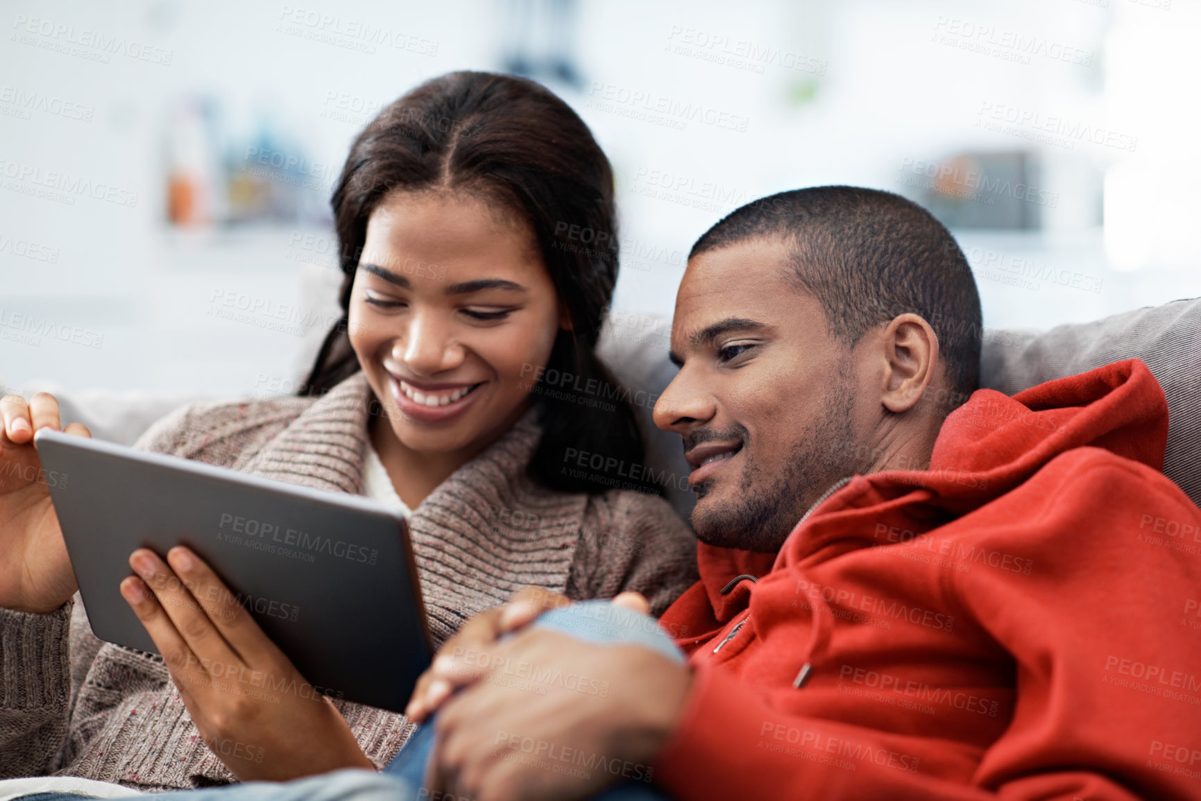 Buy stock photo Shot of a smiling young couple sitting on their sofa using a digital laptop