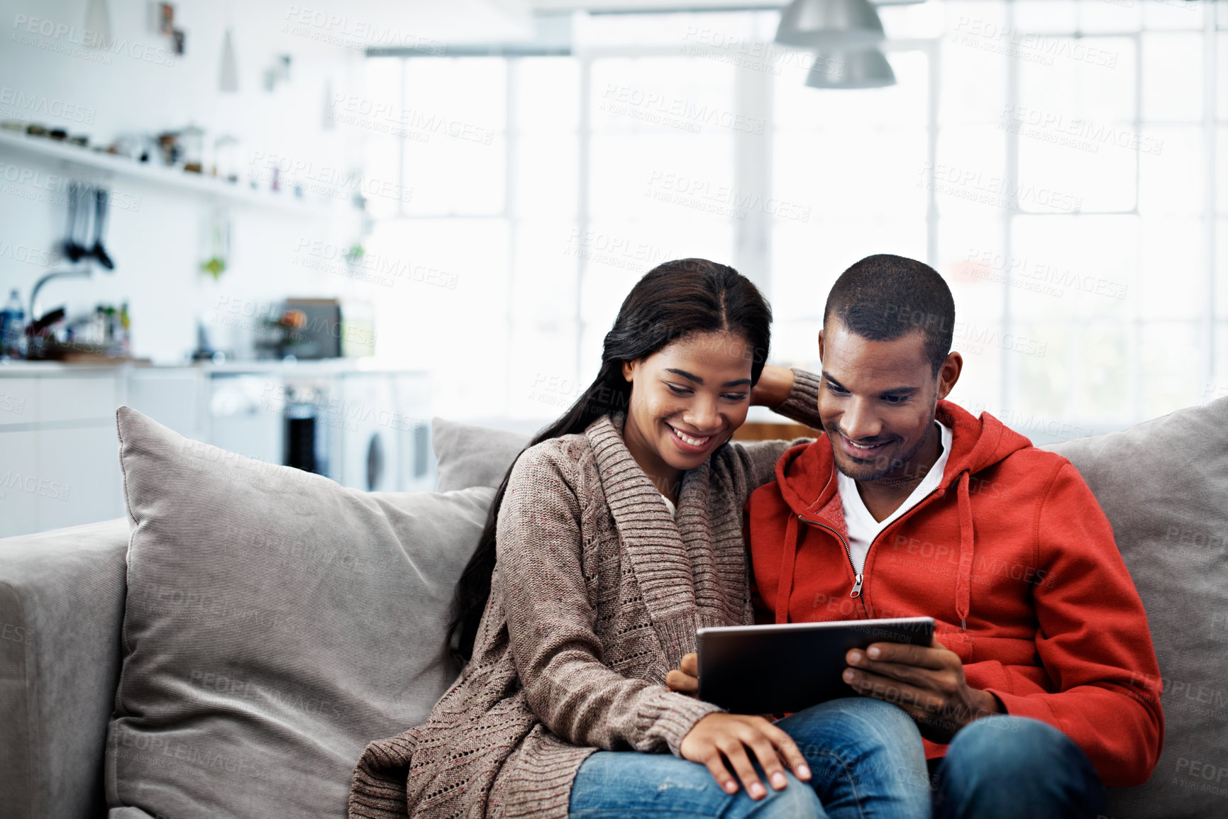 Buy stock photo Shot of a smiling young couple sitting on their sofa using a digital laptop