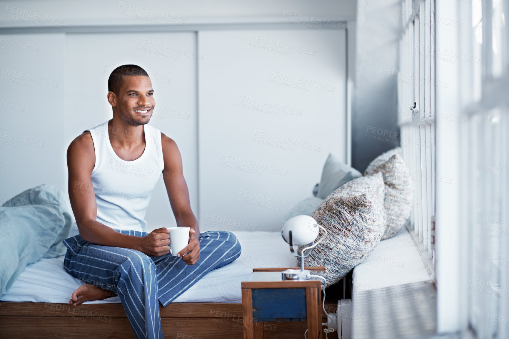 Buy stock photo Morning, smile and man with coffee in bedroom to start day, thinking and relax in home with window. House, happy person and beverage in bed for inspiration, reflection and view from apartment