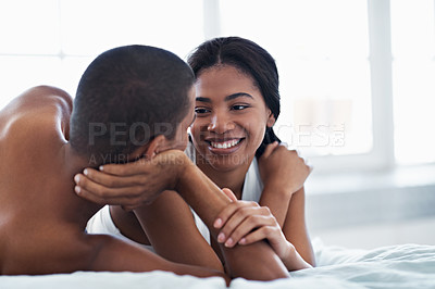 Buy stock photo Shot of a happy young couple talking together while lying in bed