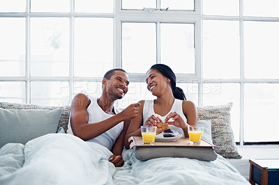 Buy stock photo Shot of a smiling young couple enjoying breakfast in bed together