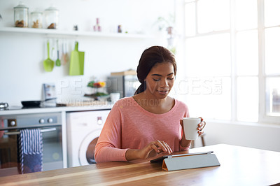 Buy stock photo Shot of a young woman using a digital tablet in the kitchen