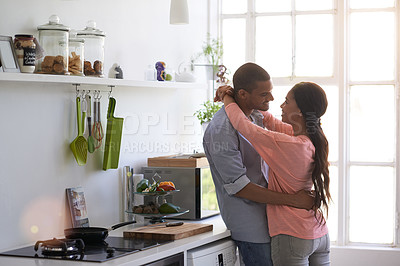 Buy stock photo Shot of an affectionate young couple hugging in the kitchen