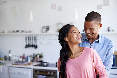 Buy stock photo Shot of an affectionate young couple hugging in the kitchen