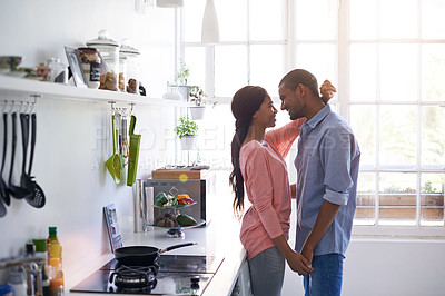Buy stock photo Shot of an affectionate young couple hugging in the kitchen