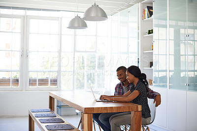 Buy stock photo Shot of a young couple sitting at their dining table using a latpop