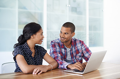 Buy stock photo Shot of a young couple sitting at their dining table using a latpop