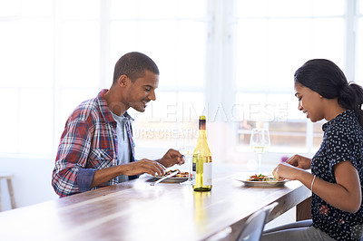 Buy stock photo Shot of a young couple eating dinner in their kitchen