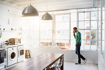 Buy stock photo Shot of a young man using his cellphone in the kitchen