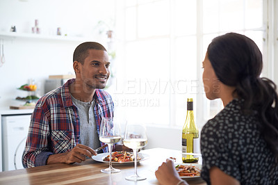 Buy stock photo Shot of a young couple talking together over dinner in their kitchen