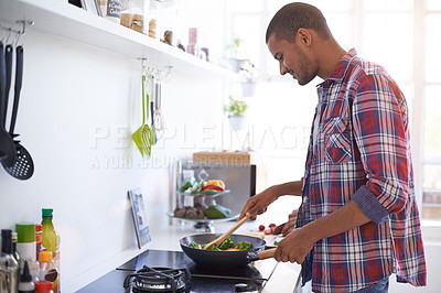 Buy stock photo Shot of a young man cooking on the stove in the kitchne