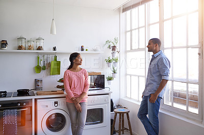 Buy stock photo Shot of a young couple talking together in their kitchen