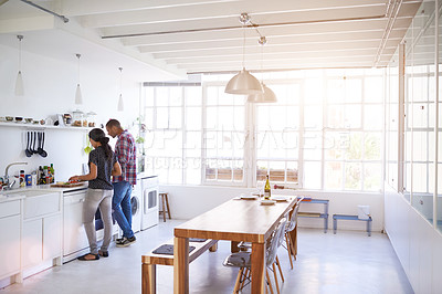 Buy stock photo Shot of a young couple cooking a meal together in their kitchen