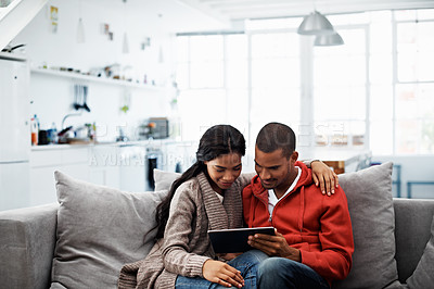 Buy stock photo Shot of a smiling young couple sitting on their sofa using a digital laptop