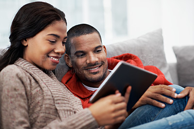 Buy stock photo Shot of a smiling young couple sitting on their sofa using a digital laptop