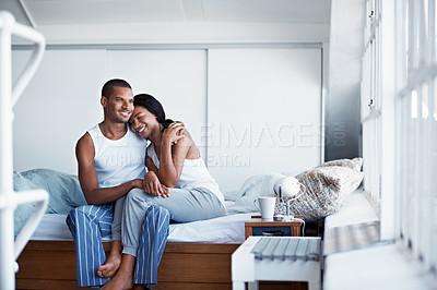 Buy stock photo Shot of a happy young couple sitting on their bed