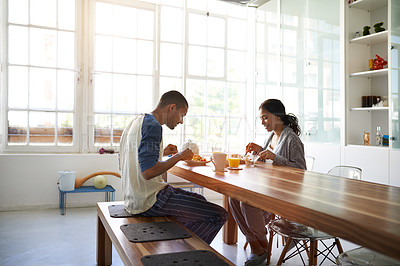 Buy stock photo Shot of a young couple eating breakfast together in their kitchen